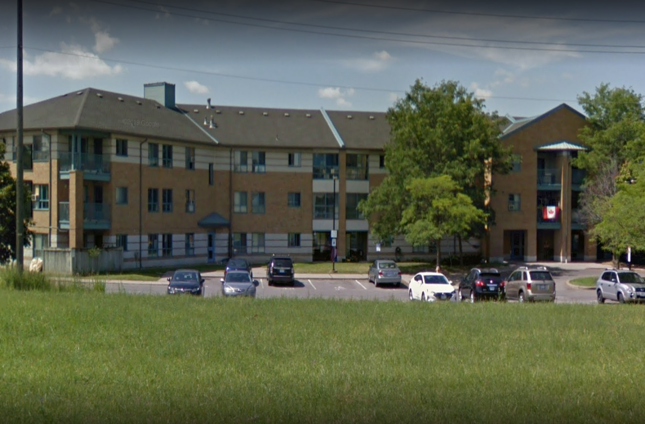 Exterior of Watermark building.  Several trees and a parking lot are in view